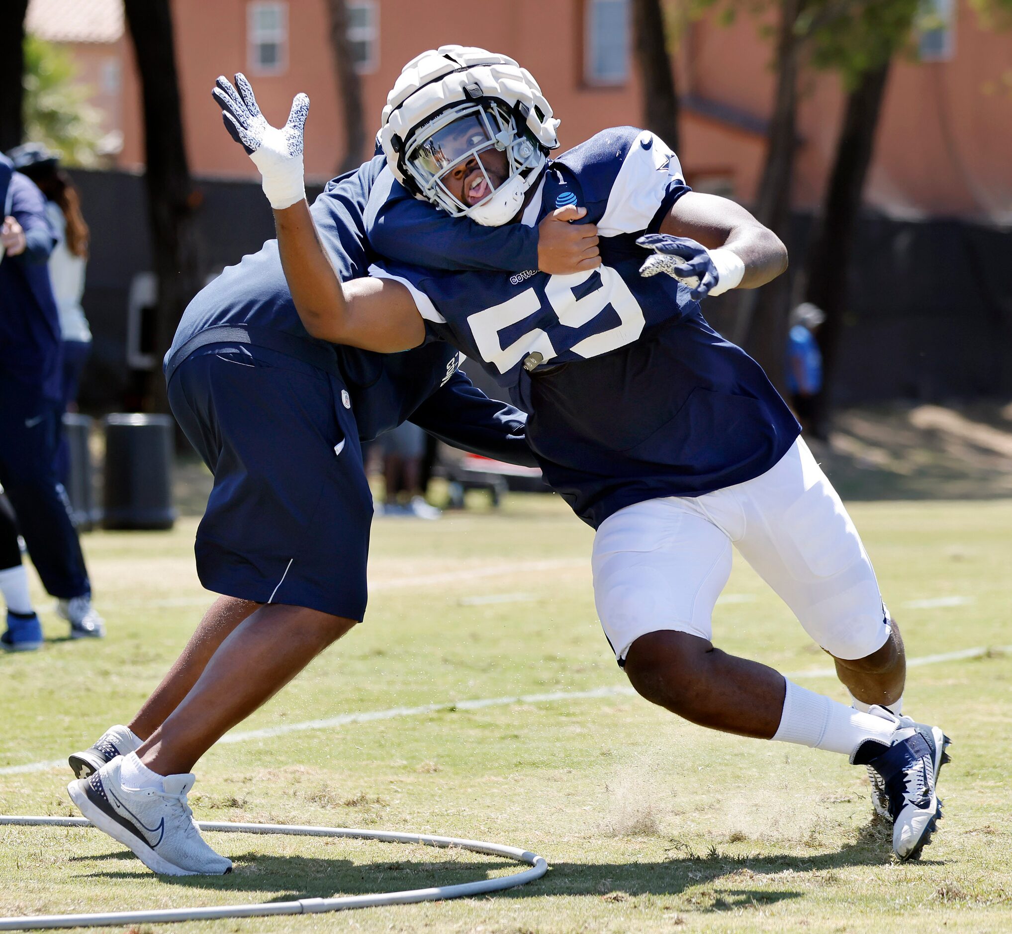 Dallas Cowboys defensive end Markaviest Bryant (59)  is fought off by defensive line coach...