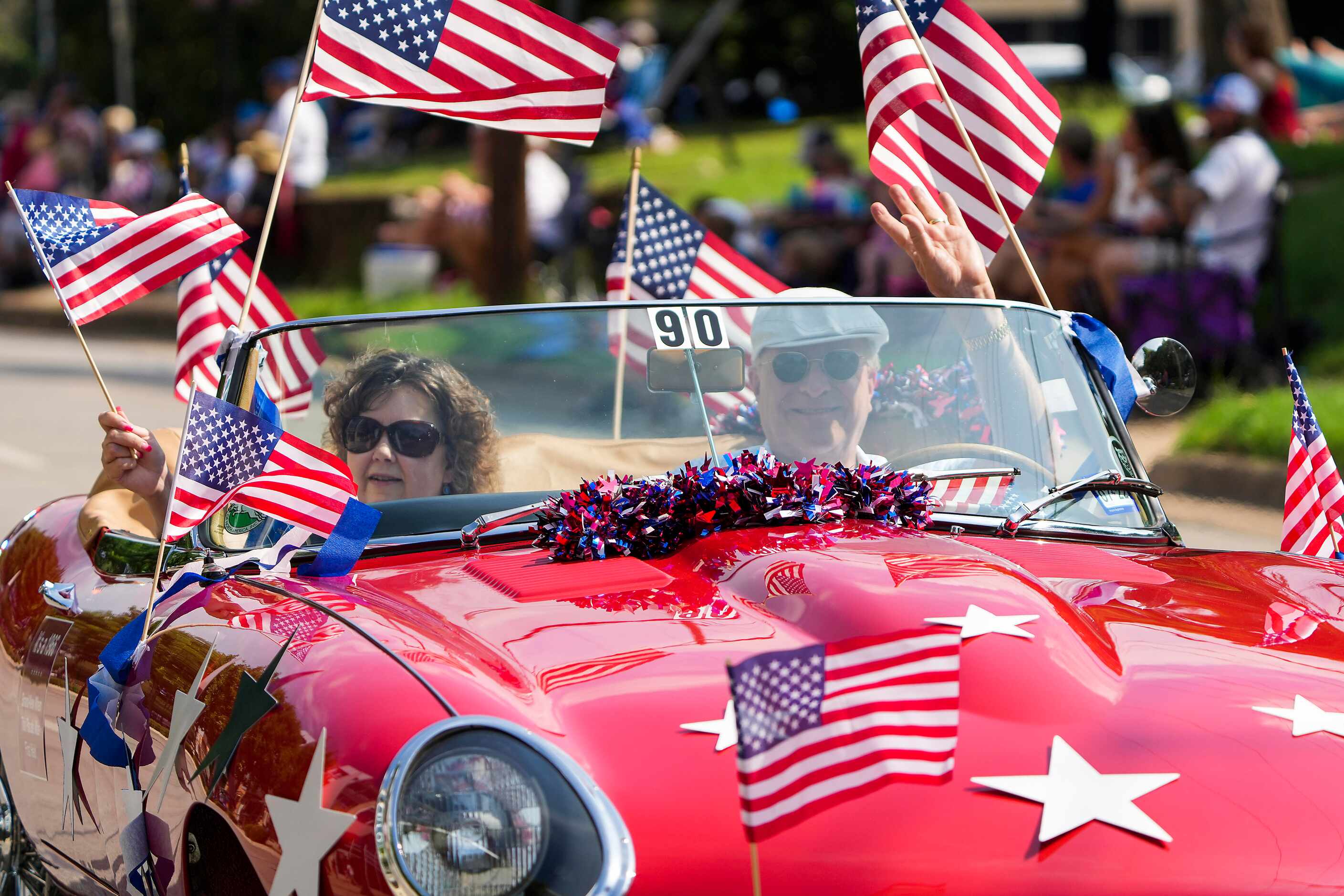 Clark Kirby waves his 1966 Jaguar decked out in red, white and blue during the Arlington...