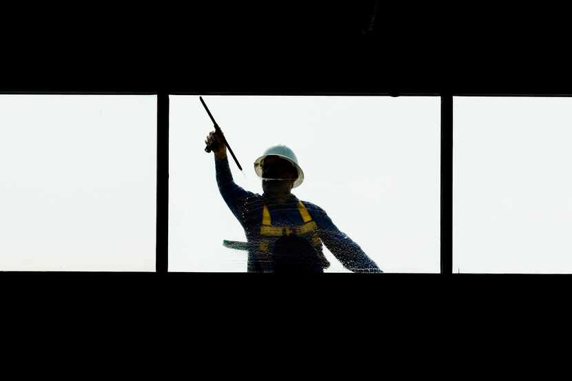 A construction worker wipes the window outside the creative office of Assembly Park, a...