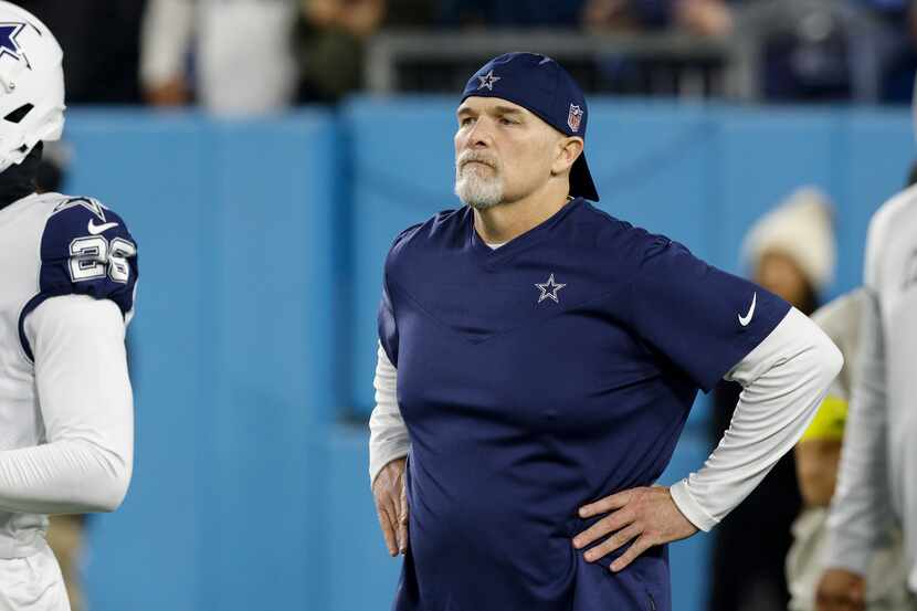 Dallas Cowboys defensive coordinator Dan Quinn watches players warm up before an NFL game at...