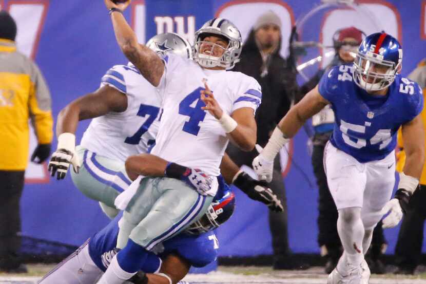 Dallas Cowboys quarterback Dak Prescott (4) gets a pass away under intense pressure from New...