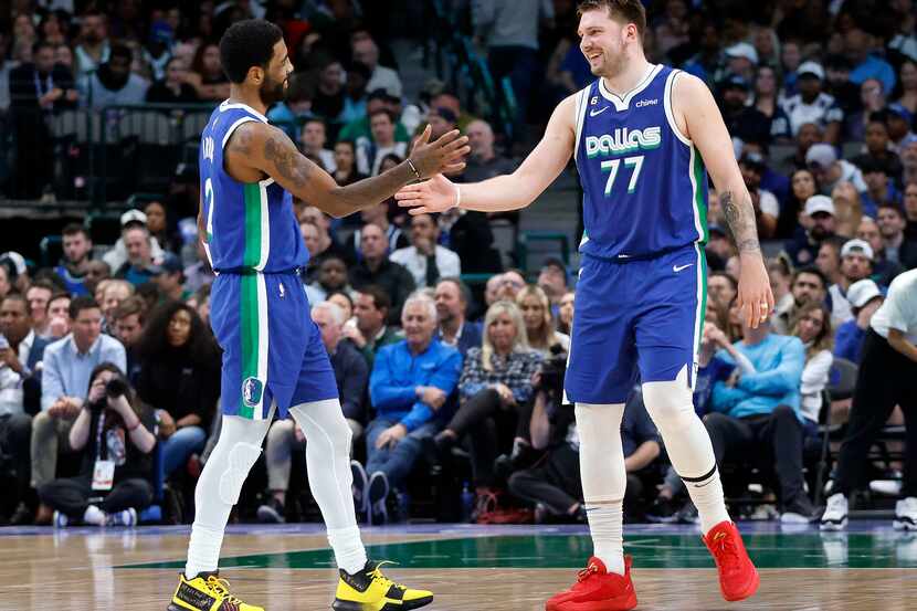 Dallas Mavericks guards Kyrie Irving (2) and Luka Doncic (77) spa hands following a second...