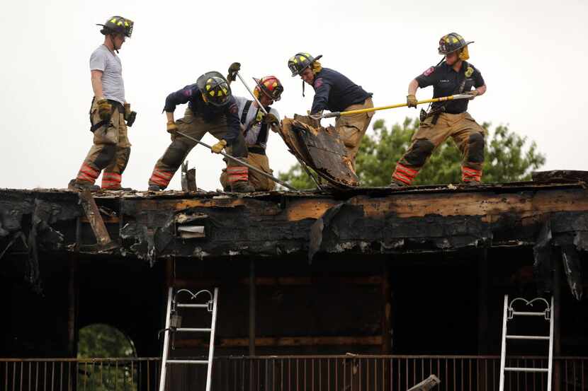 Arlington firefighters worked to put out hot spots on the roof of an apartment complex  in...