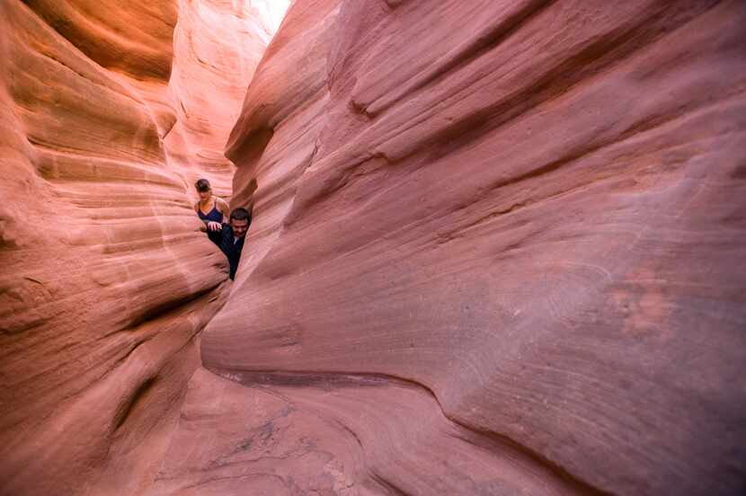 Two hikers squeeze through Peek-a-Boo Canyon in the Grand Staircase-Escalante National...