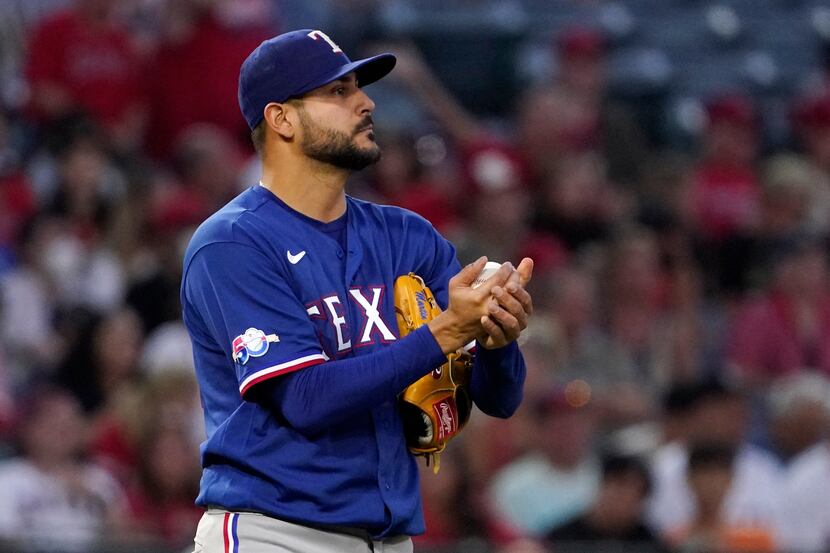 Texas Rangers starting pitcher Martin Perez rubs the ball after giving up a double to Los...