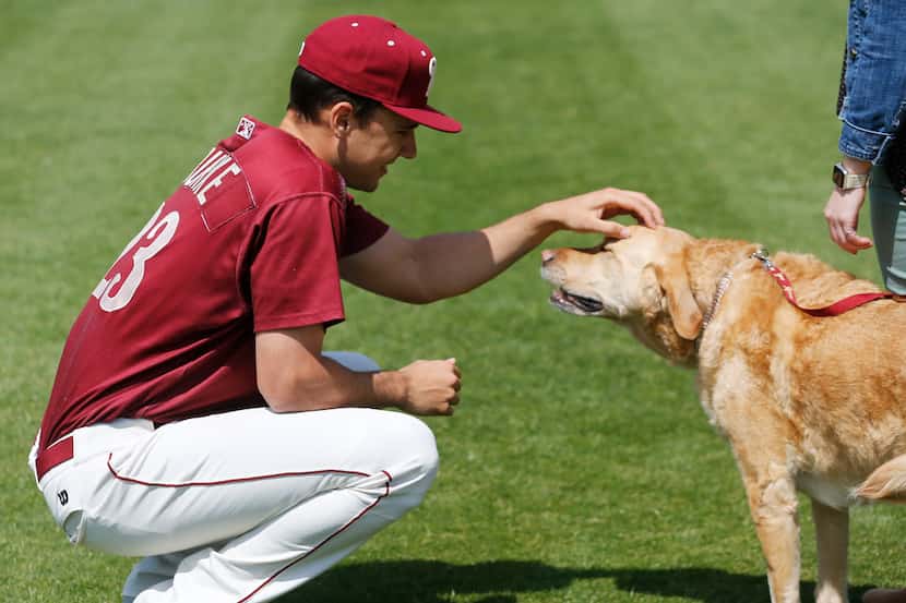 Frisco RoughRiders pitcher Brock Burke (23) pets Brooks, the team dog, before taking a team...