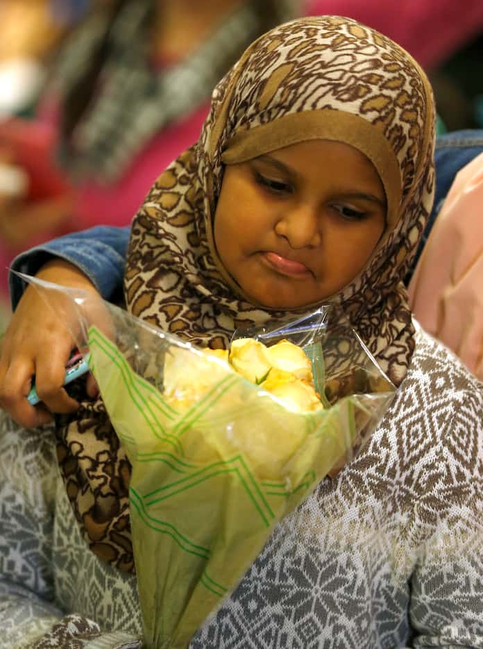 Muzen Elnur, 11, holds flowers while she waits for her grandmother from Sudan, who was being...