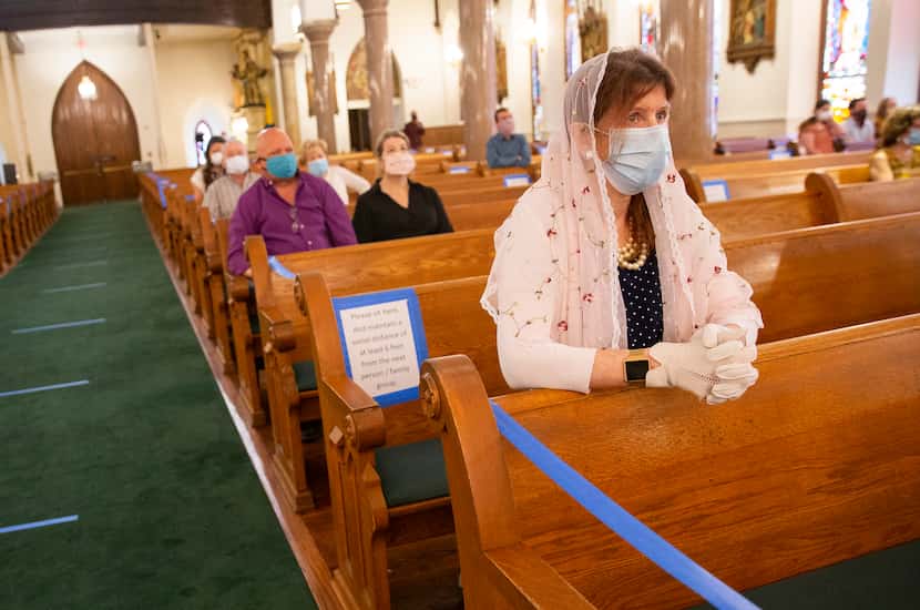 Cheri Robertson from Richardson kneels as she waits for Mass to begin at St. Patrick...