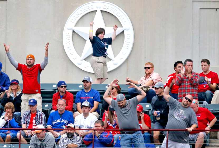 Texas Rangers usher Hannah Speirs tries to help rally the troops as she is pictured in...