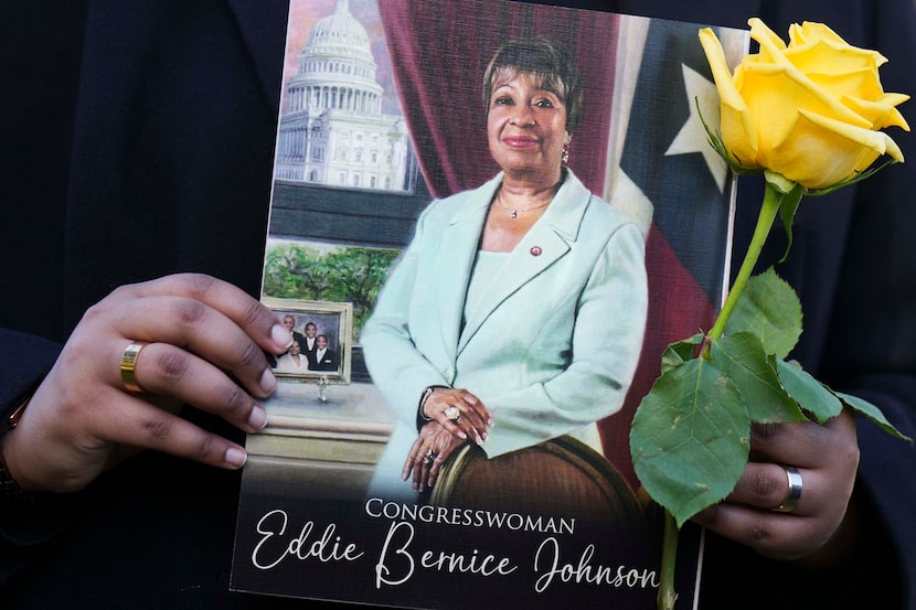 A mourner holds a yellow rose along with a funeral program during burial services for former...