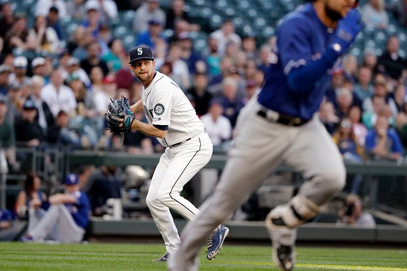 Seattle Mariners starting pitcher Mike Leake, left, turns to throw to first base after...