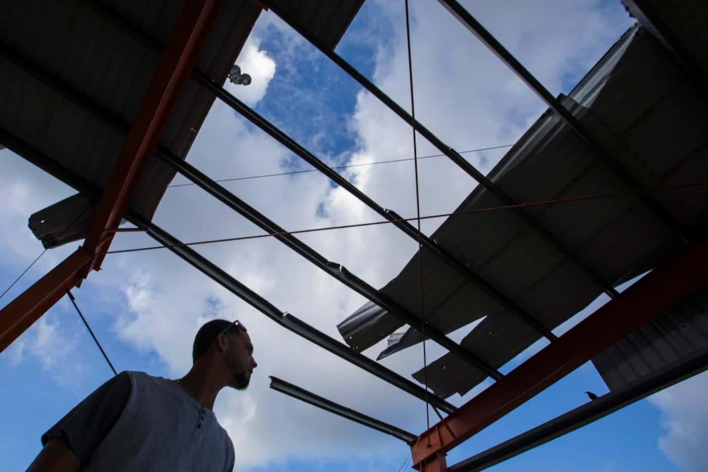 Rangers pitcher Alex Claudio looks over a roof destroyed by Hurricane Maria on a grandstand...