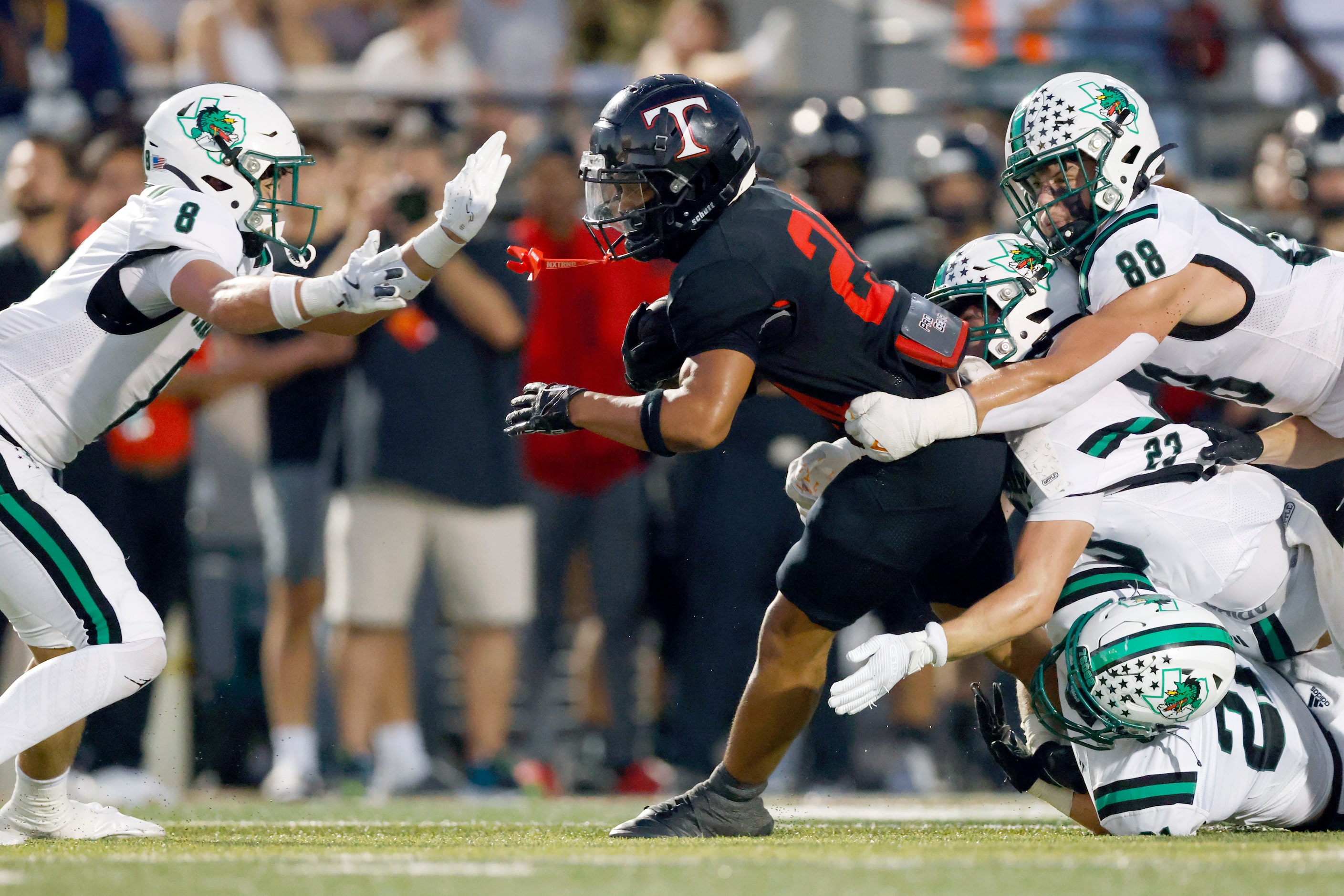 Euless Trinity running back Josh Bell (20) is tackled by several Southlake Carroll defenders...