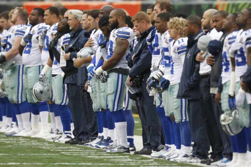 Dallas Cowboys players and coaches bow their heads in a moment of silence for practice squad...