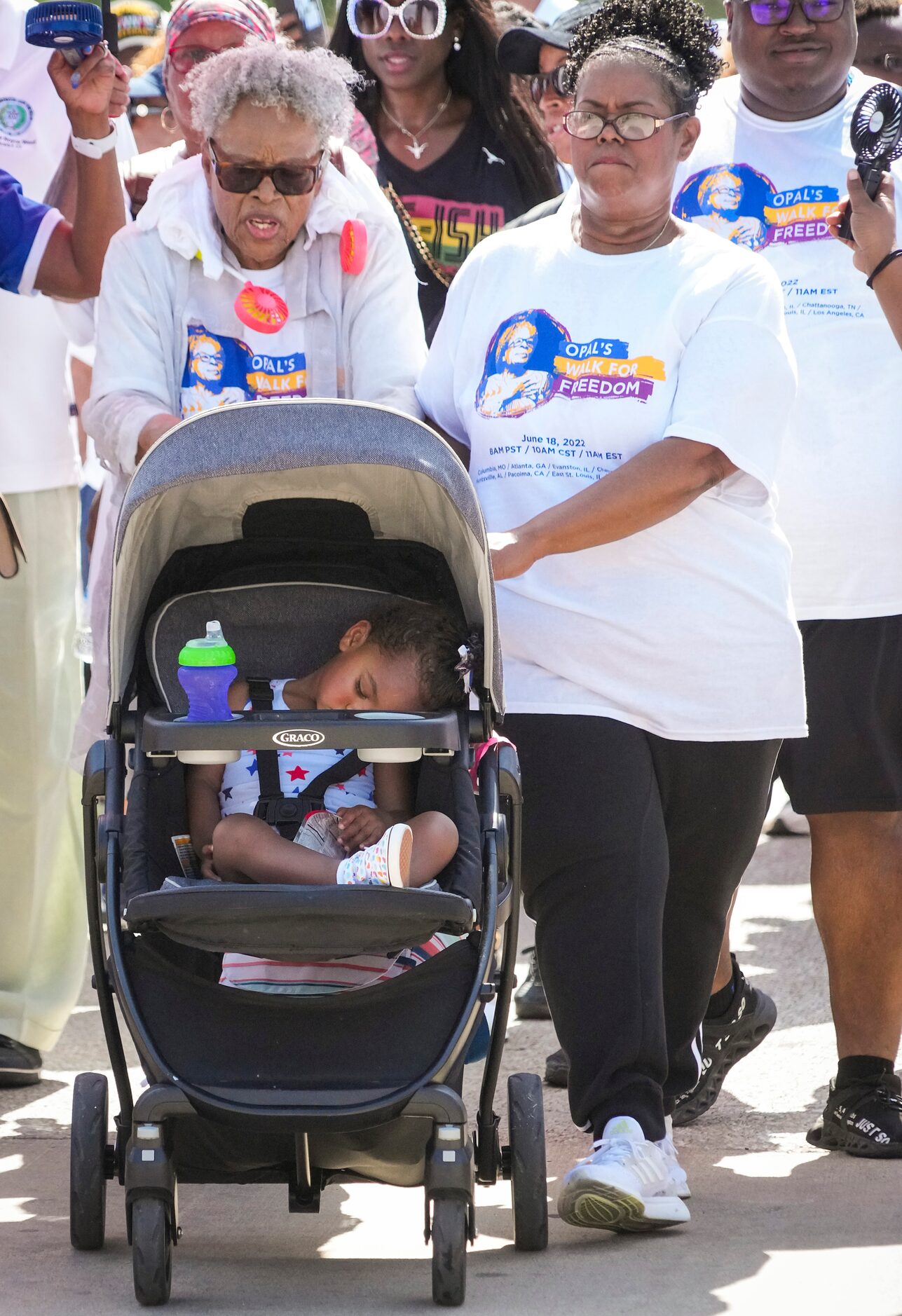 Opal Lee pushes one of her great granddaughters in a stroller as she leads walkers up...