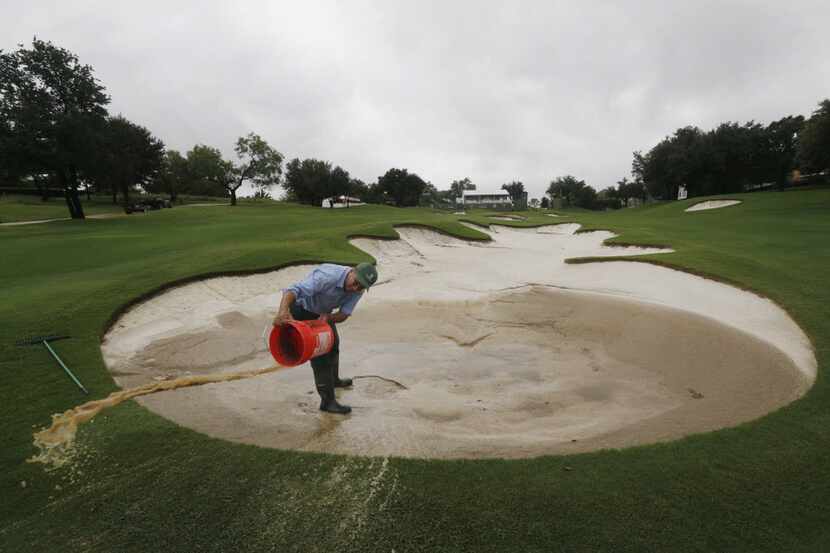 Victor Rodriguez clears water from a sand trap on the 16th fairway during a scheduled three...