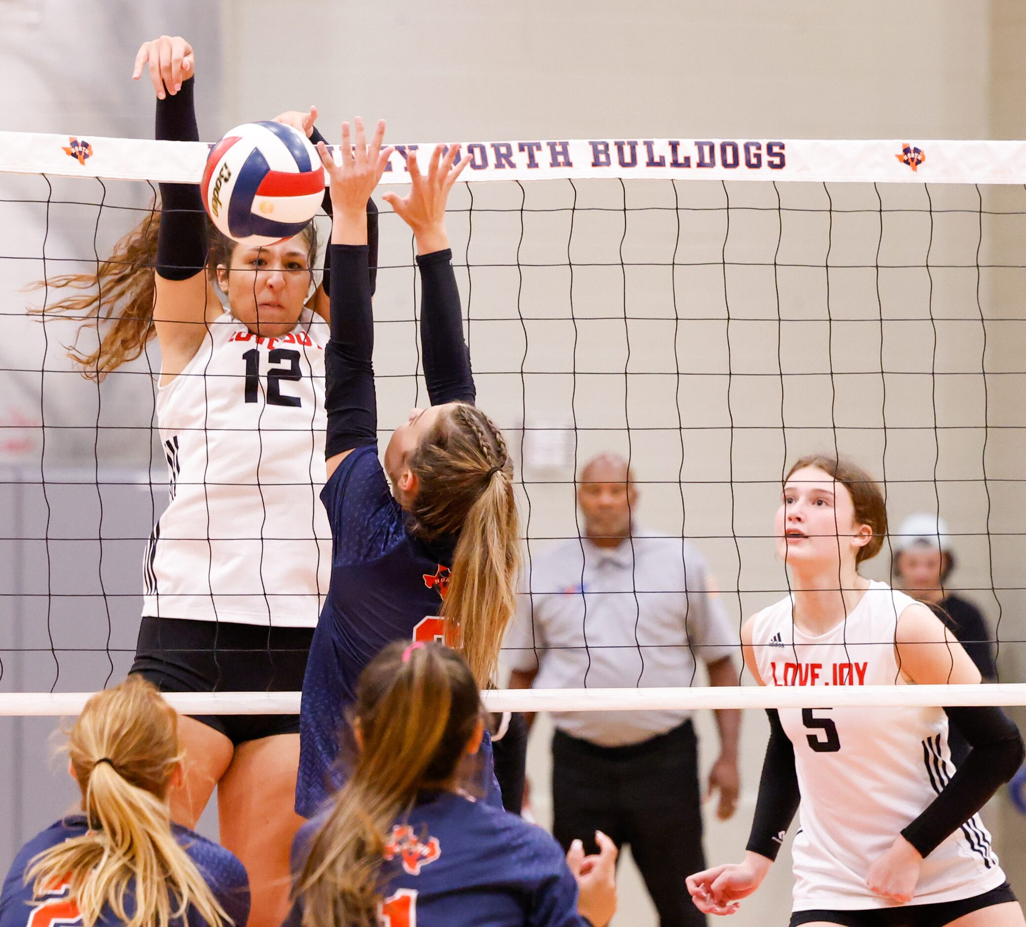 Lovejoy Hannah Gonzalez (12) spikes the ball into McKinney North defenders at a match in...