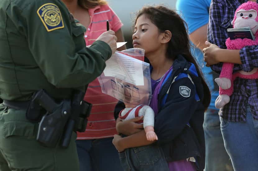 Salvadoran immigrant Stefany Marjorie, 8, watches as a U.S. Border Patrol agent records...