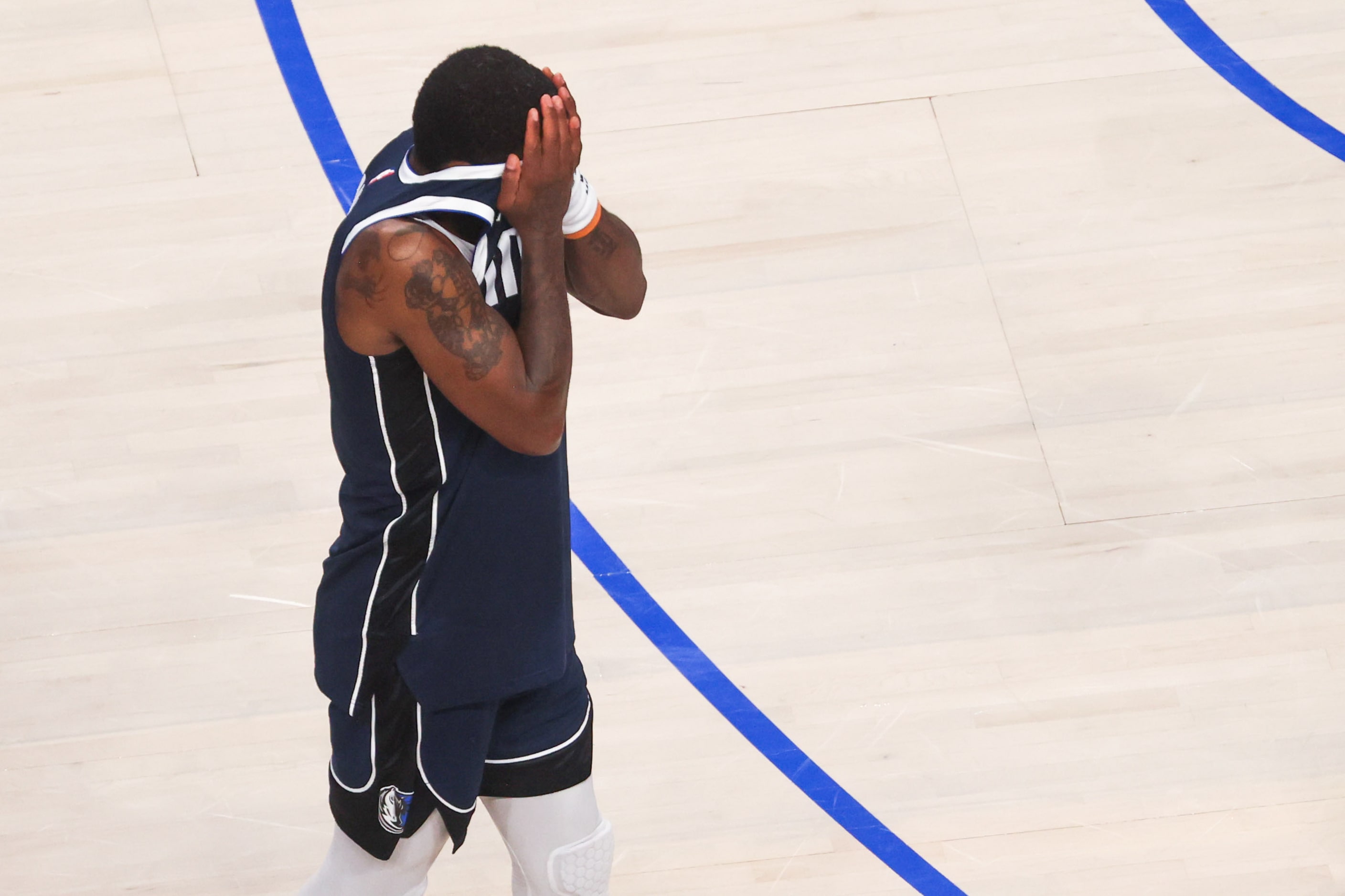 Dallas Mavericks guard Kyrie Irving covers his faces as he exits the court after a loss to...