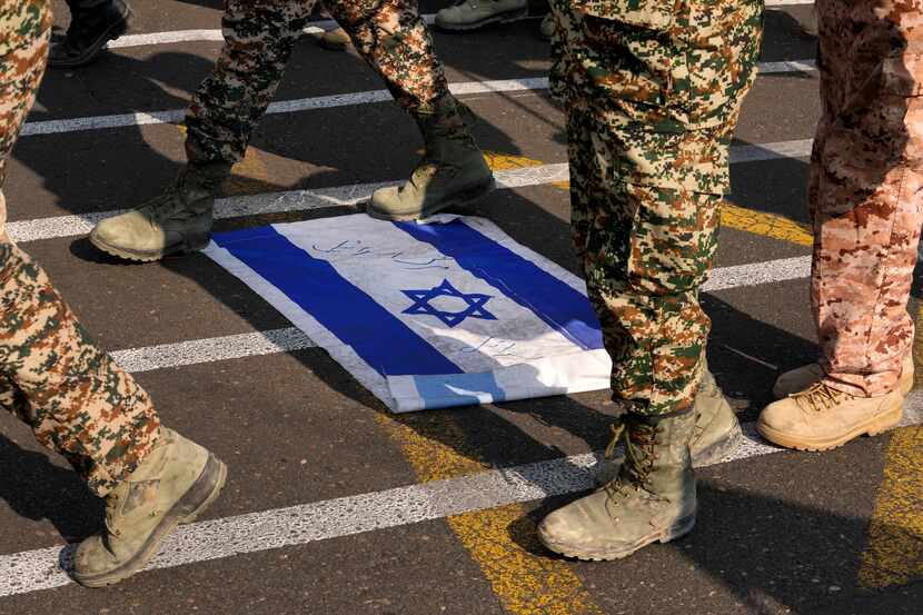 Members of the Iran's Basij paramilitary force march on a representation of the Israeli flag...
