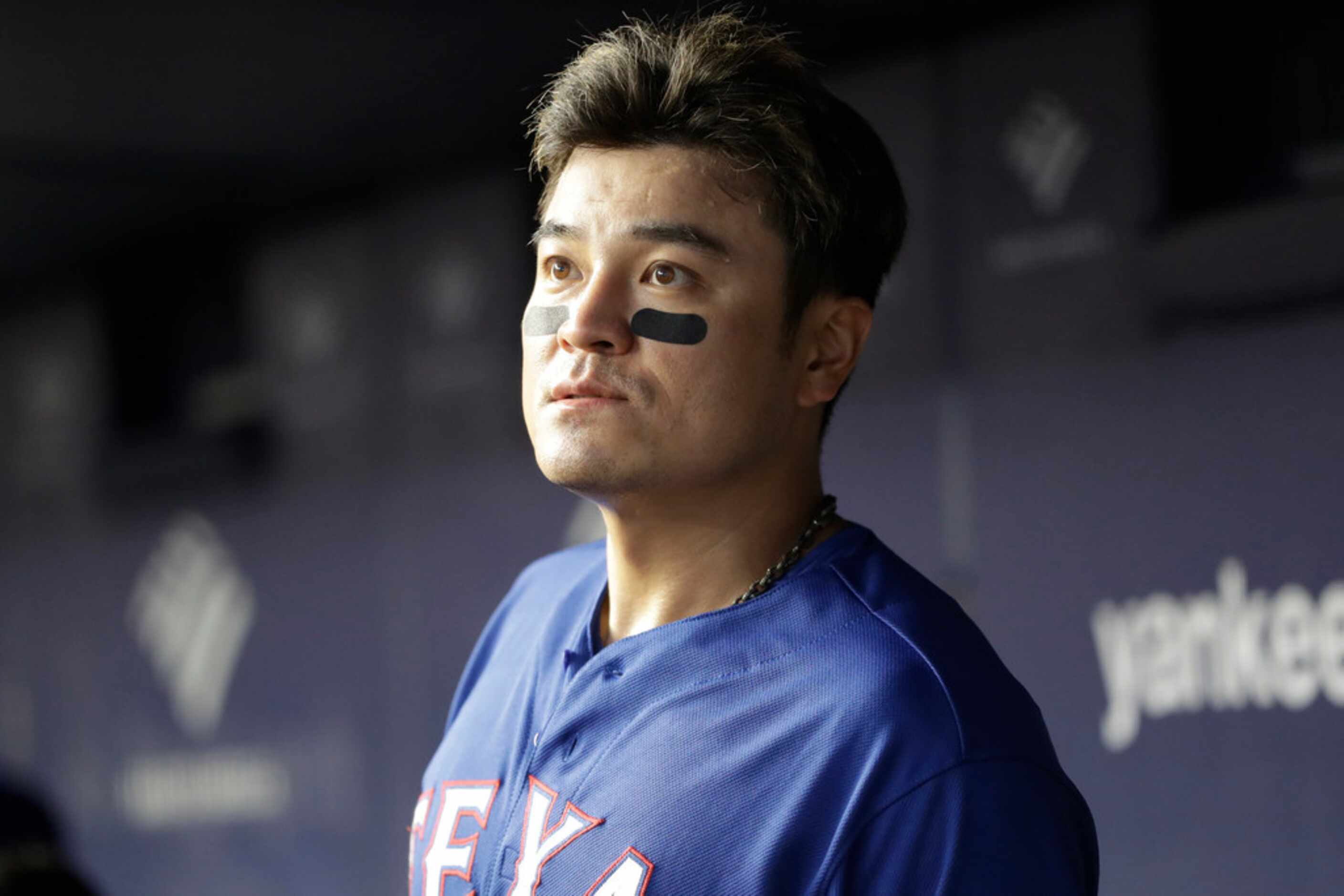 Texas Rangers' designated hitter Shin-Soo Choo peers out from the dugout during a baseball...