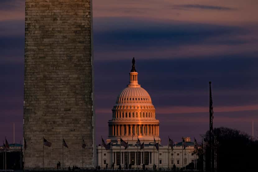 The U.S. Capitol is seen past the Washington Monument as the sun sets on Saturday, Dec. 26,...