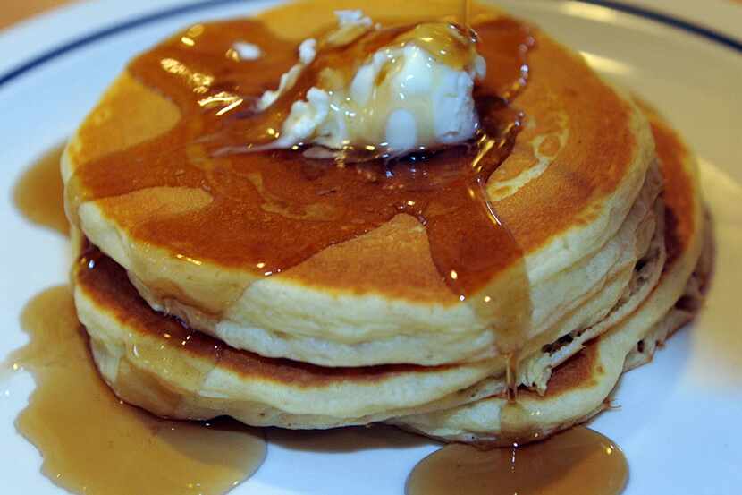 Maple syrup runs down the side of a short stack of three pancakes at the International House...