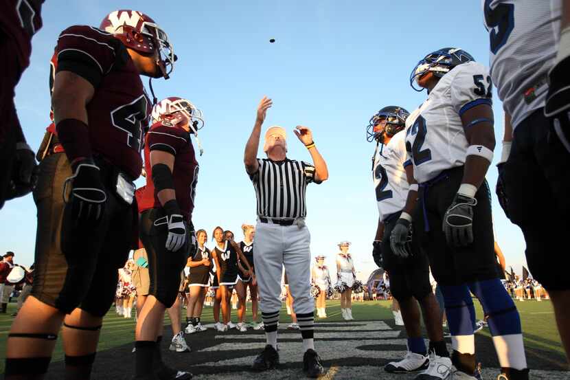 Referee Al Skuza flips the coin before the start of a high school football game between...