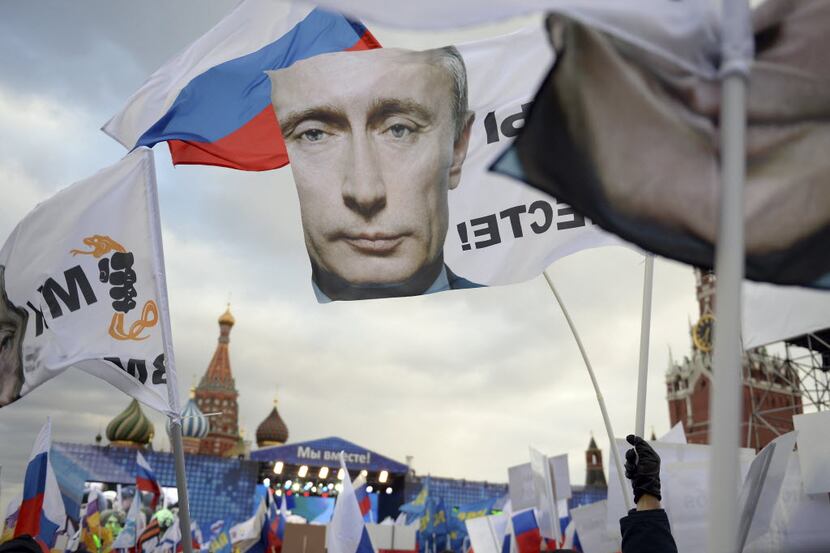 Demonstrators gather, carrying Russian flags and flags showing President Vladimir Putin's...
