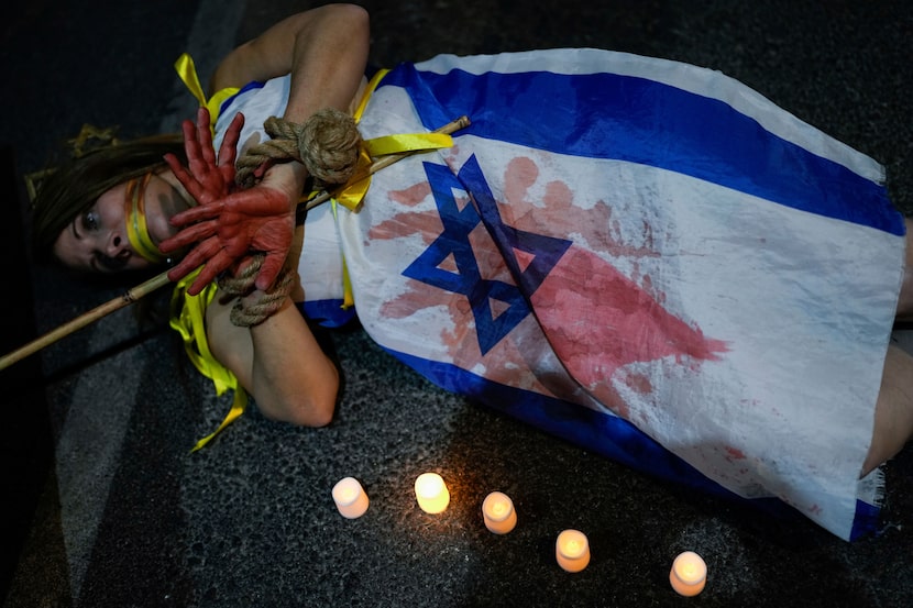 A demonstrator is painted red, symbolizing blood, during a protest calling for the immediate...