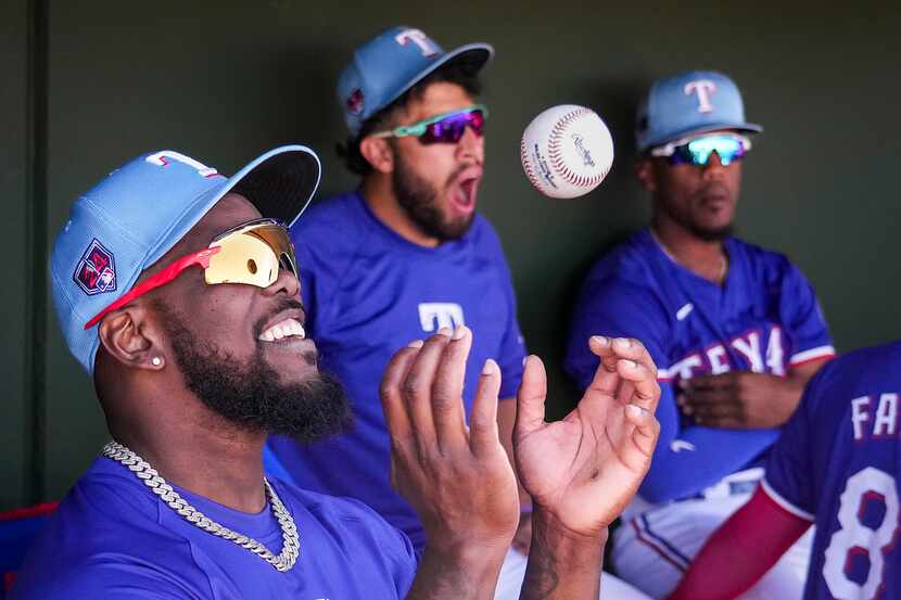 Texas Rangers outfielder Adolis García tosses a ball in the dugout during the third inning...