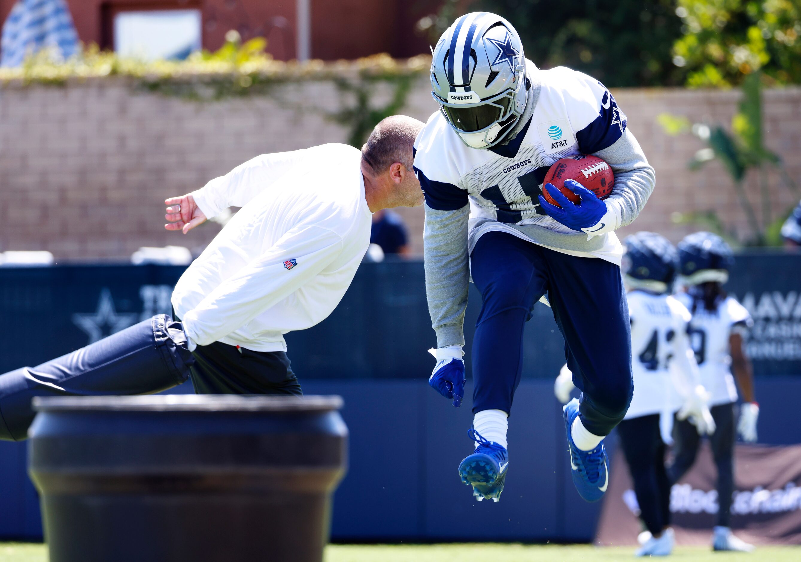 Dallas Cowboys running back Ezekiel Elliott (15) leaps past a blocking pad during a training...