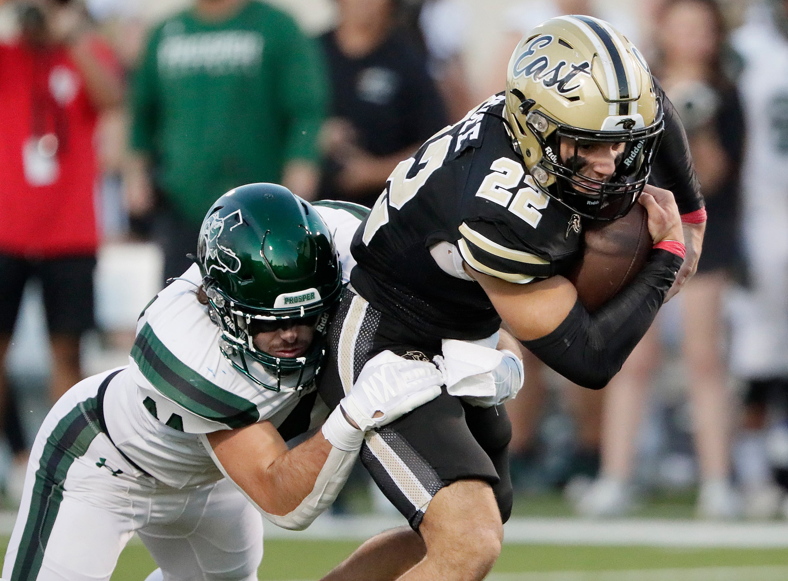 Plano East High School running back Travis Agee (22) is tackled by Prosper High School...