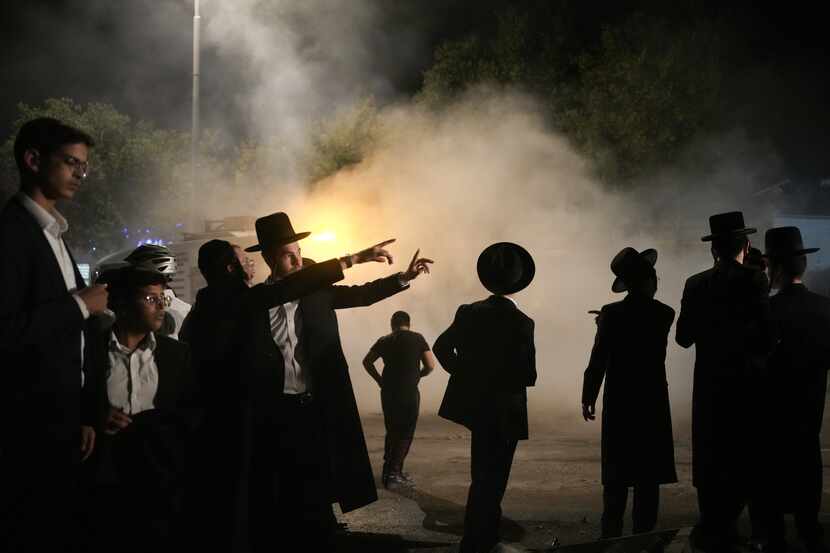 Ultra-Orthodox Jewish men inspect a damaged road after it was hit by a rocket fired from the...