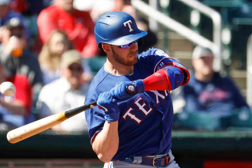 Texas Rangers catcher Mitch Garver takes a ball during the first inning of a spring training...
