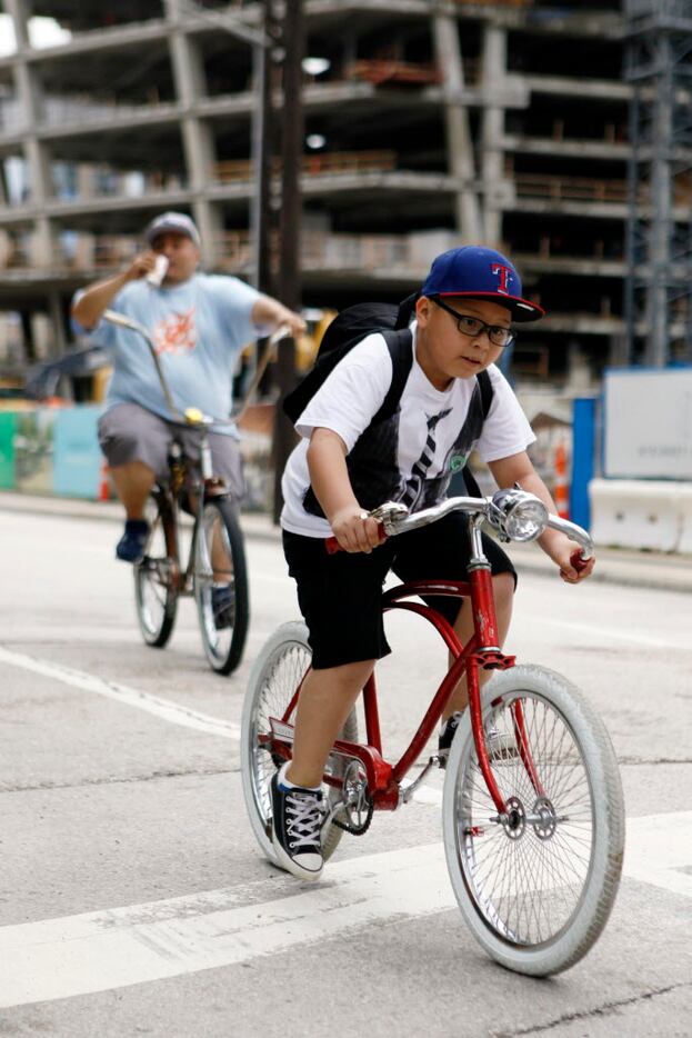 Damien Gomez, 8, rides his bicycle with his dad closely behind him on North Olive Street...