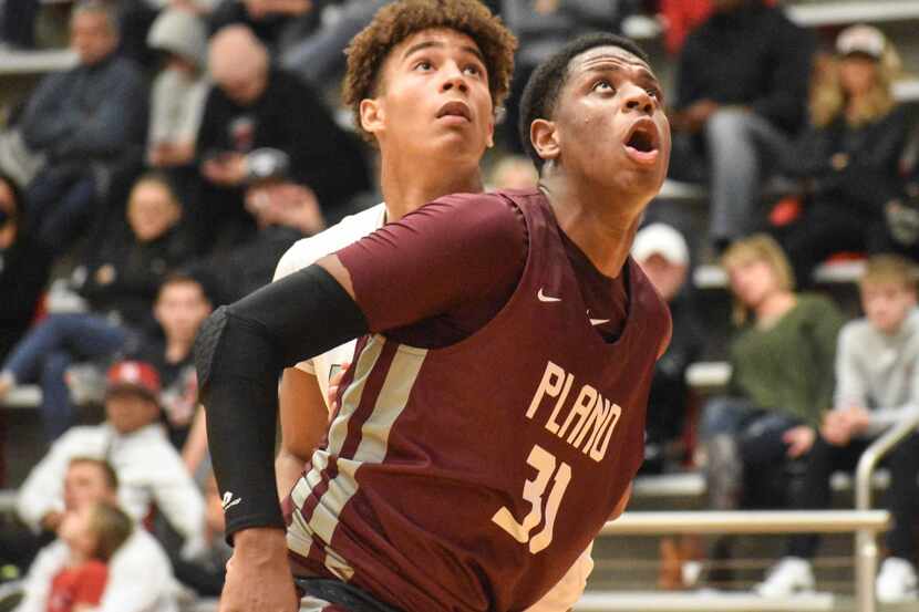 Plano junior Justin McBride (right) boxes out for a rebound against Flower Mound Marcus on...