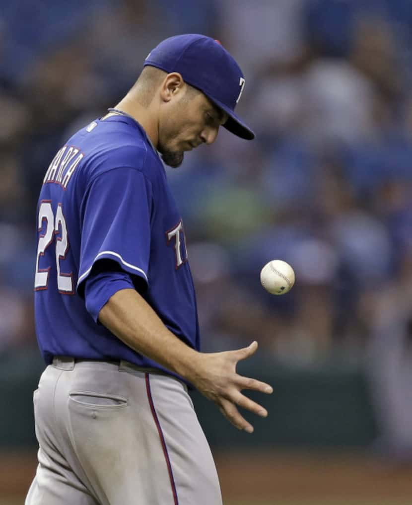 Texas Rangers starting pitcher Matt Garza flips the ball as manager Ron Washington heads to...