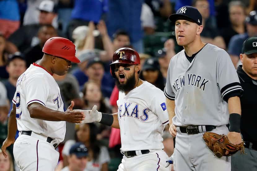 Texas Rangers third base coach Tony Beasley, left, celebrates a two-run triple hit by...