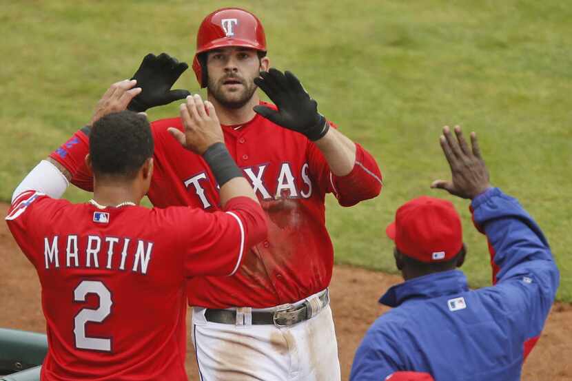Texas' Mitch Moreland is congratulated at the dugout by Leonys Martin (2) and manager Ron...