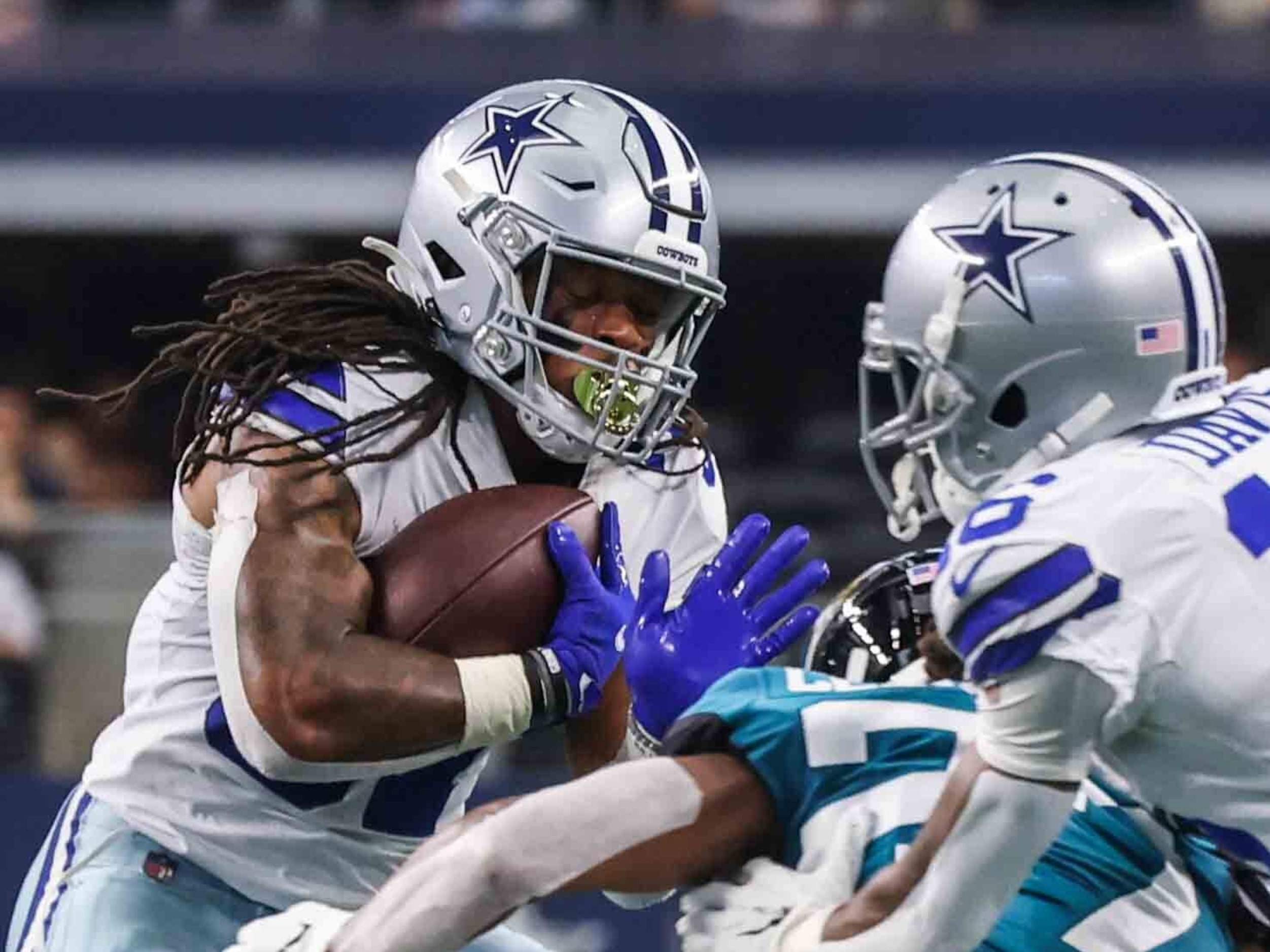 El corredor de los Cowboys de Dallas, JaQuan Hardy (der), protege el balón en un acarreo...