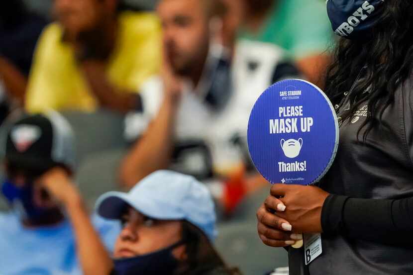 A stadium worker holds a sign reminding fans to wear their face masks during the second...