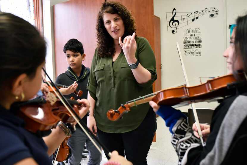 Teacher Nicole Melki demonstrates finger technique for violin with Hennessy Toscano, left,...