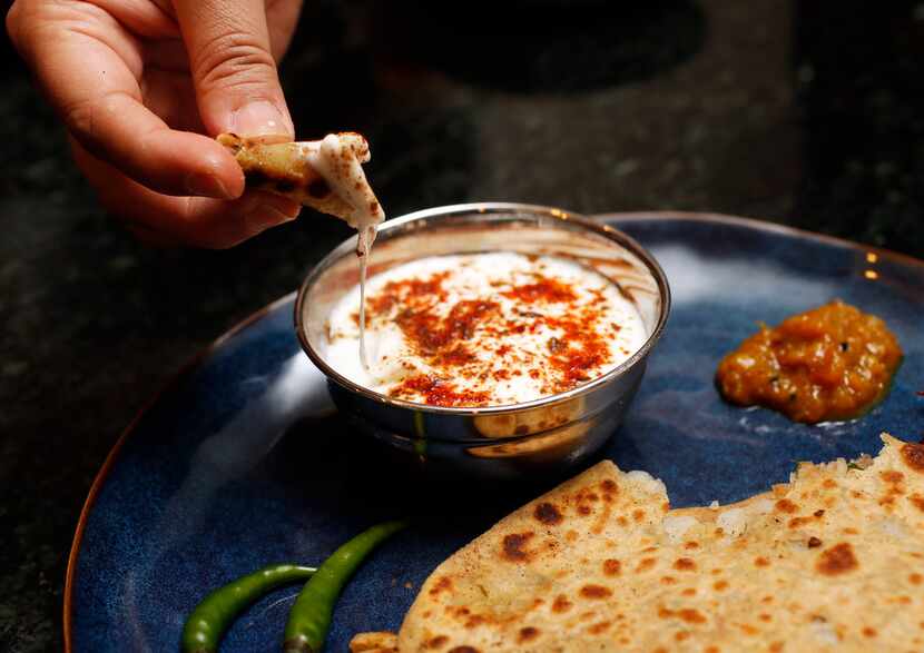 Sapna Punjabi-Gupta dips a paratha in yogurt and spices.