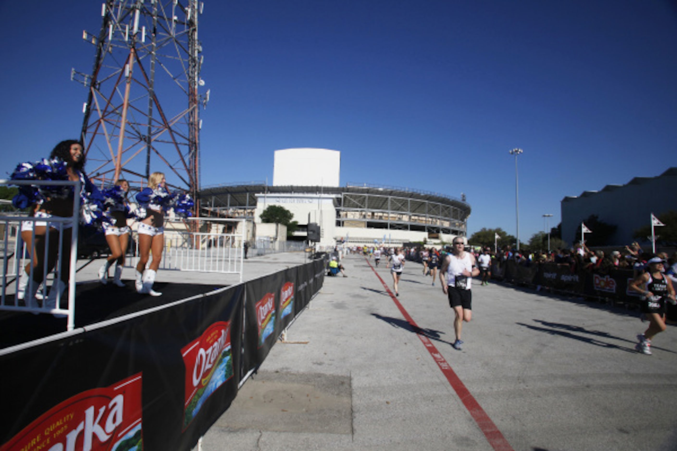 Running participants make their way into Fair Park past the Dallas Cowboy cheerleaders...