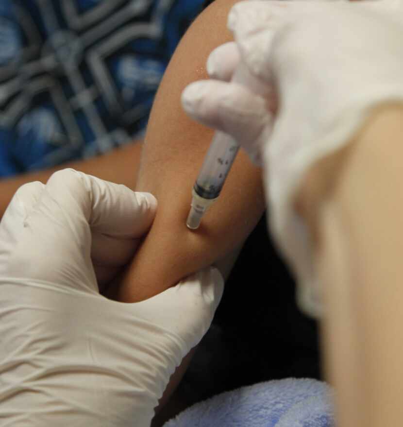Registered nurse Nicole Kay gives Dilan Lara, 4, one of five immunizations at the Dallas...