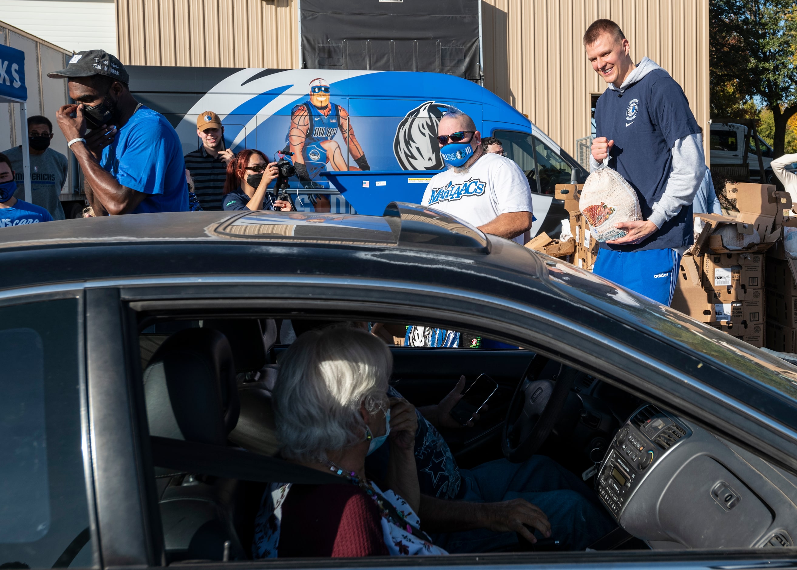 Mavs ManiAAC ProZac, left, and Mavericks player Kristaps Porzingis, greet families as they...