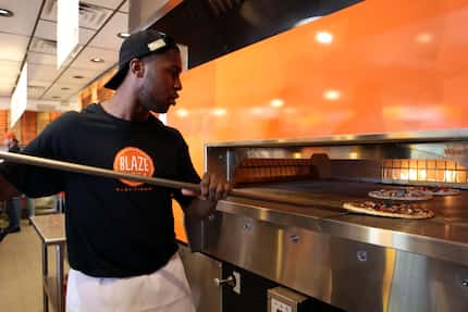 K'Len Sutton turns the pizzas in a hot open-flame oven at D-FW's first Blaze Pizza in Frisco.