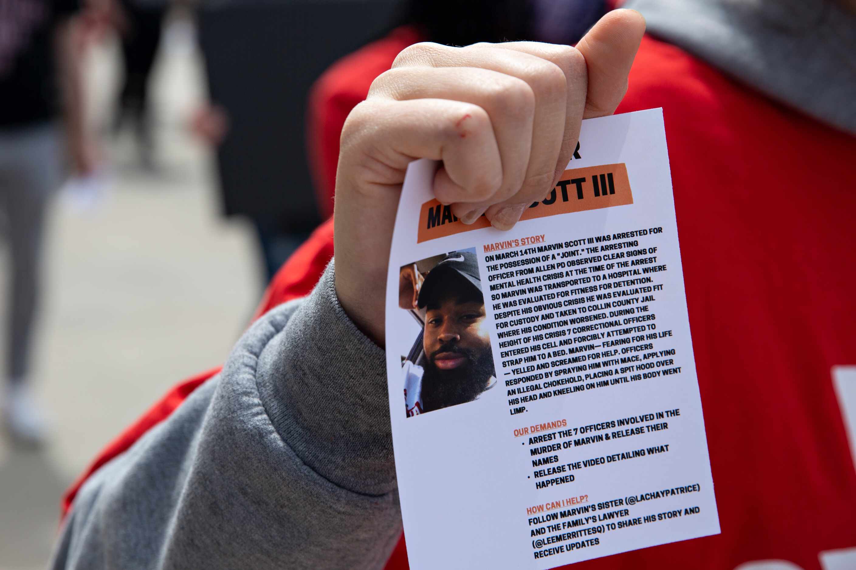 Alejandra Bernal hands out flyers containing information about Marvin Scott IIII, who died a...