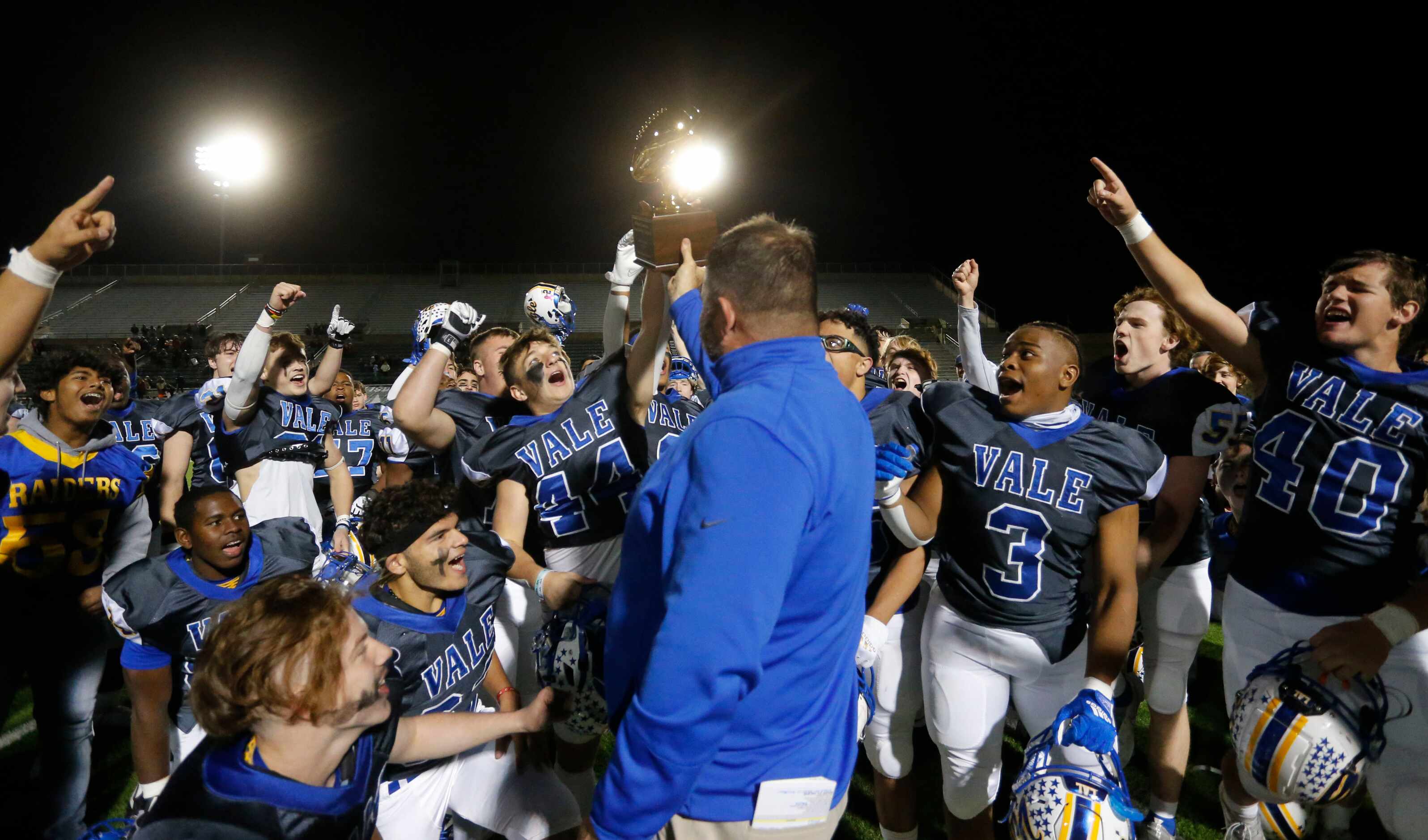 Sunnyvale players celebrate, as head football coach John Settle holds up a game trophy at...